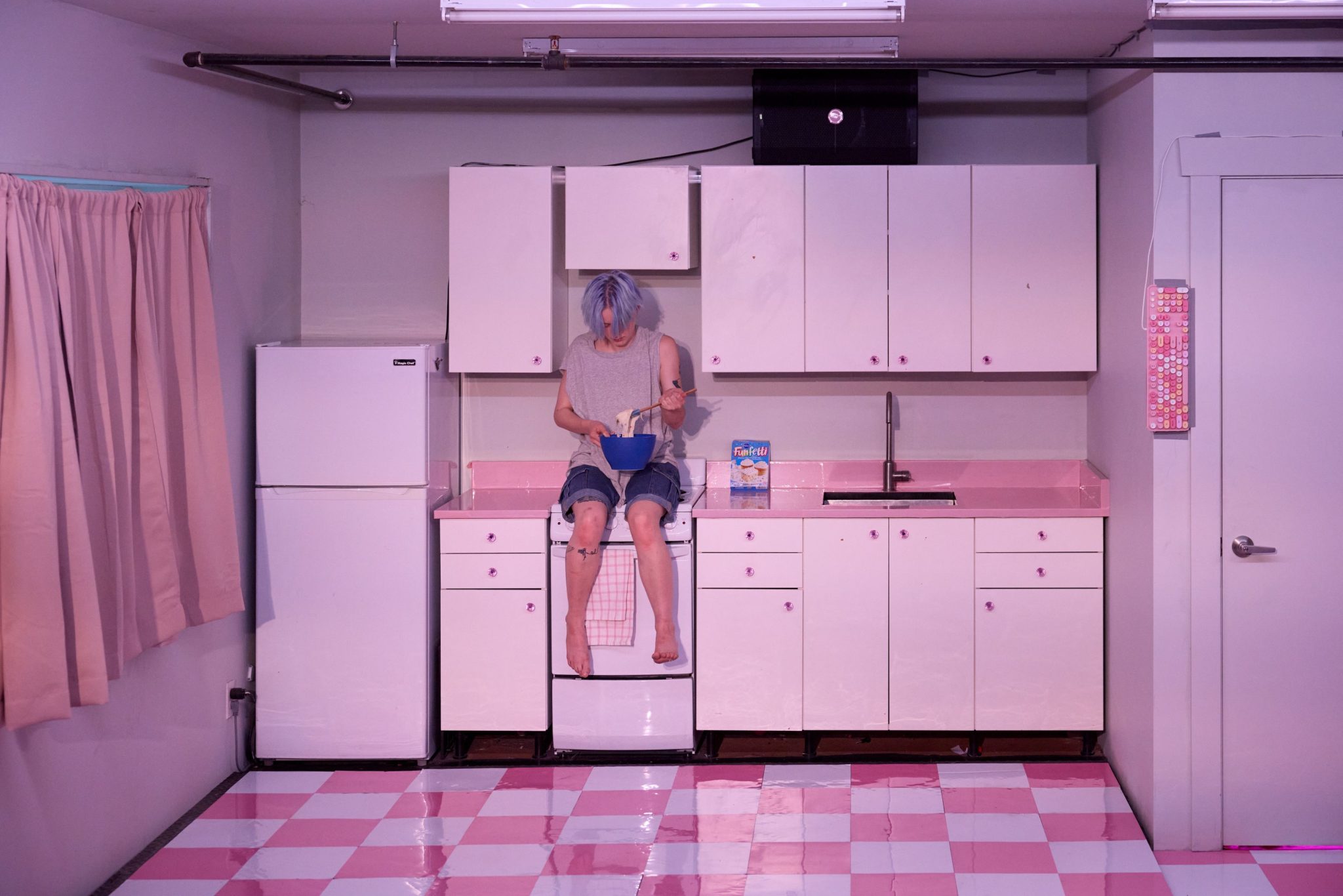 kelly sitting on top of a white counter wearing grey shirt and jean shorts