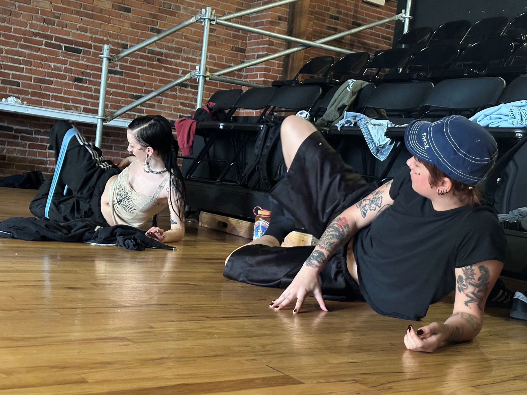 Two dancers in Ballet Rituals laying on side on wooden dance studio floor