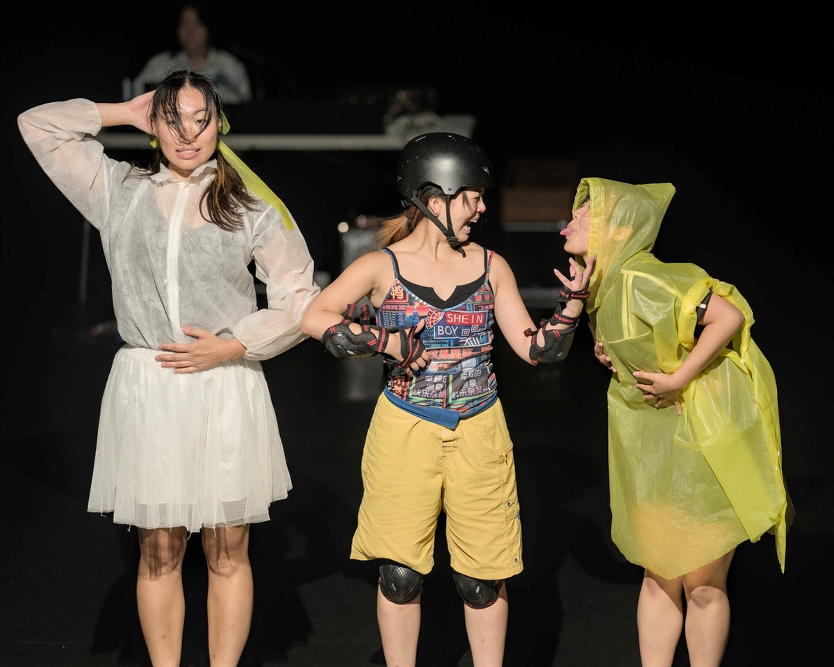3 dancers facing the audience dressed in bright yellow and white against a black background
