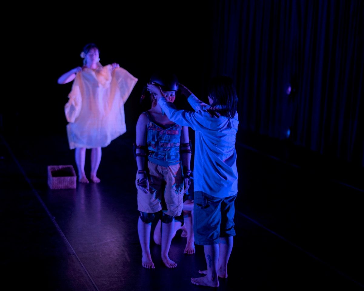 3 dances lit in blue against a dark black background