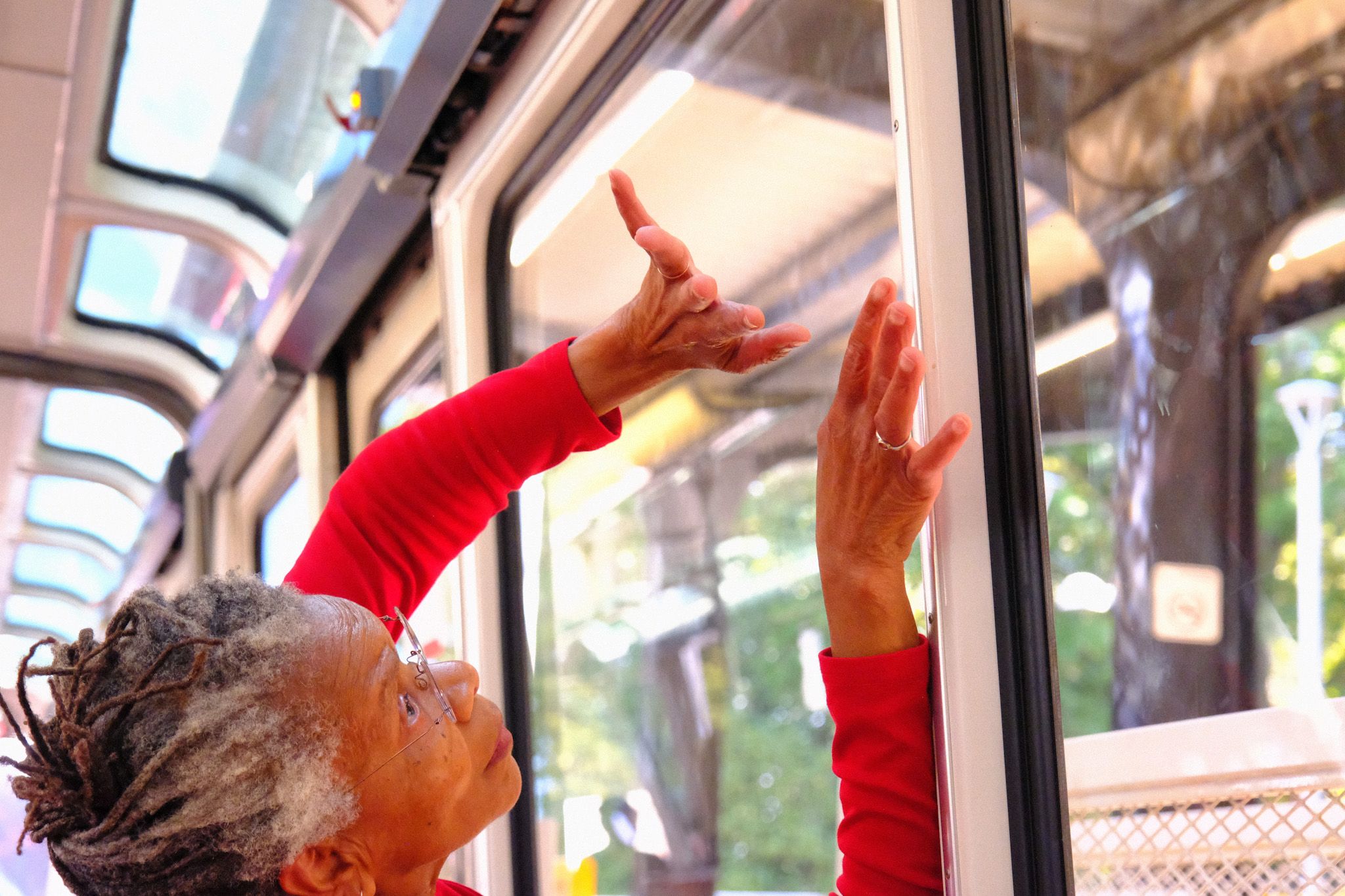 Bebe Miller wearing red touching the window glass on the monorail